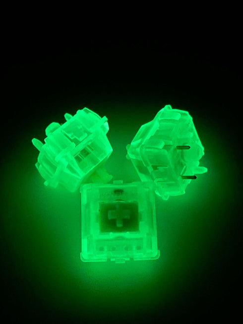 Drie Gateron Luciola switches die fel groen oplichten in een donkere omgeving – glow-in-the-dark demonstratie