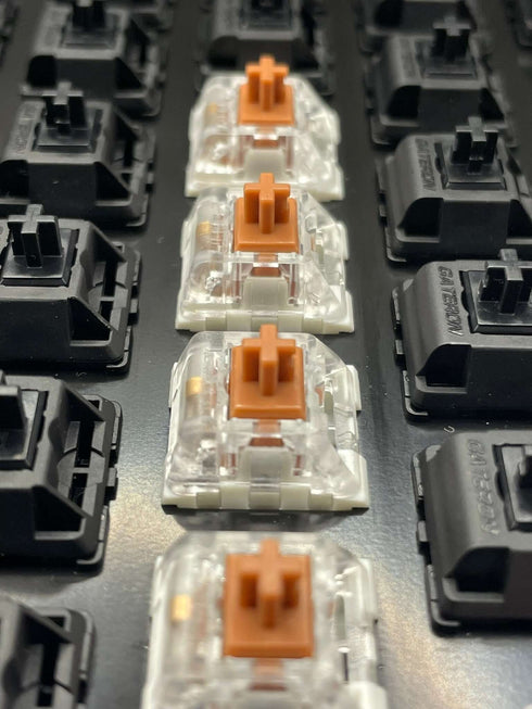 Kailh Speed Bronze switches op een toetsenbord tussen zwarte switches – bovenaanzicht