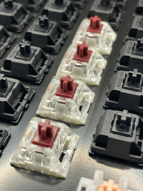 Rij Kailh Speed Coppery switches gemonteerd in een toetsenbord met rode stems en transparante behuizing.