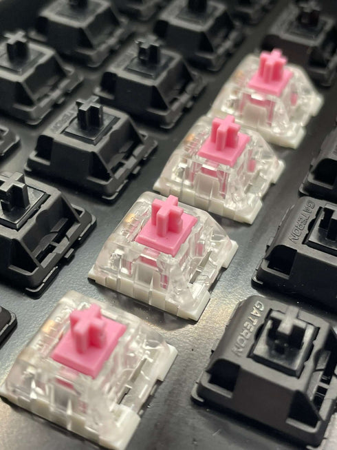 Kailh Speed Pink switches installed on a hot-swap board among black Gateron switches, viewed from the left side.