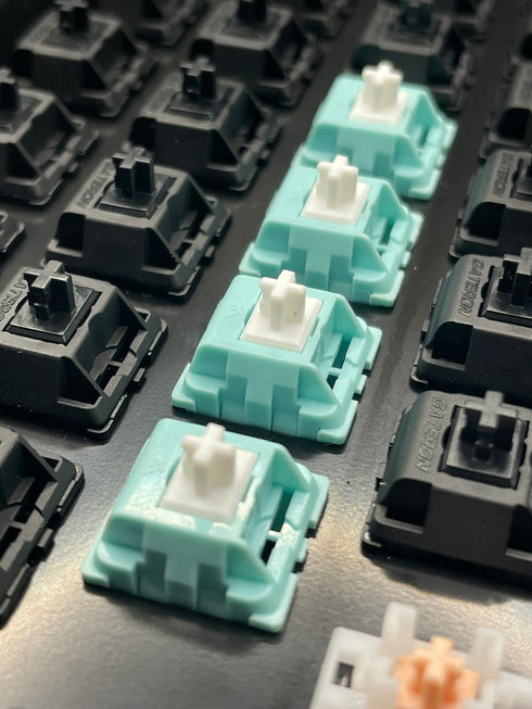 KTT Mint switches in een toetsenbord tussen zwarte switches – diagonale aanblik met witte stems