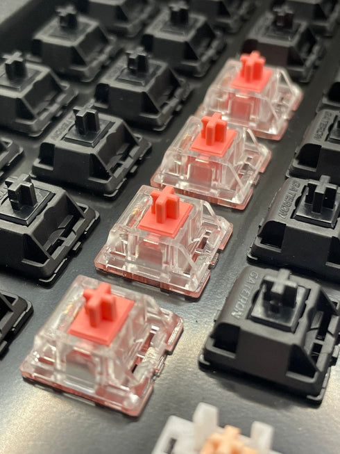 Schuin zijaanzicht van gemonteerde KTT Strawberry switches in een toetsenbord naast zwarte switches